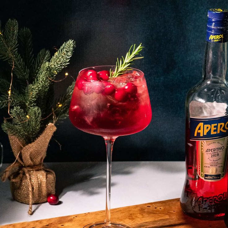 a bottle of alcohol next to a glass filled with liquid and garnished with berries