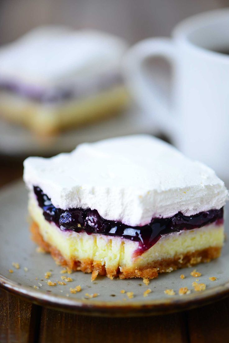 a piece of cheesecake with blueberry topping on a plate next to a cup