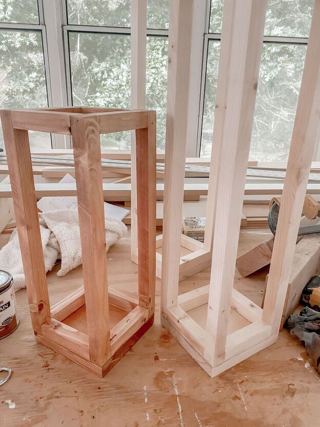 two unfinished wooden frames sitting on top of a hard wood floor next to a window