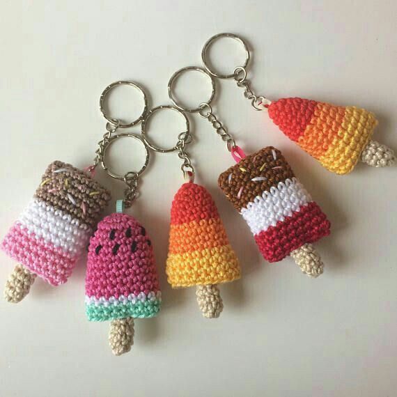 four crocheted ice cream keychains hanging on a white surface with one holding a candy cornucop and the other wearing an ice cream cone