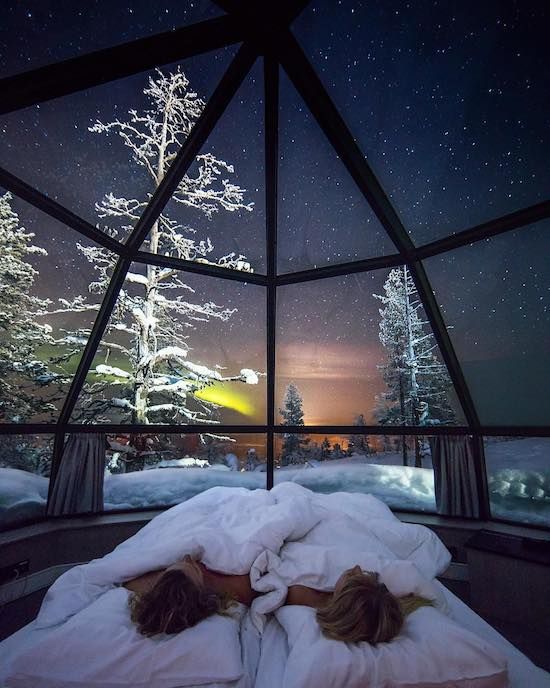 two people are sleeping in bed under the night sky and stars outside their glass dome