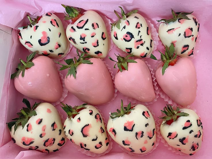 chocolate covered strawberries with pink and black spots in a pink box on the table