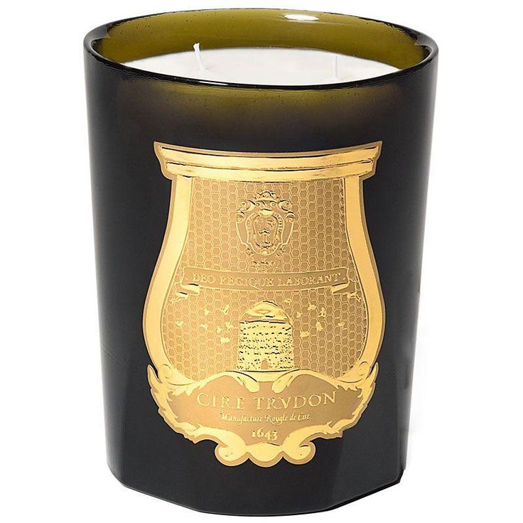 a black candle with a gold emblem on the front and sides, sitting next to a white background