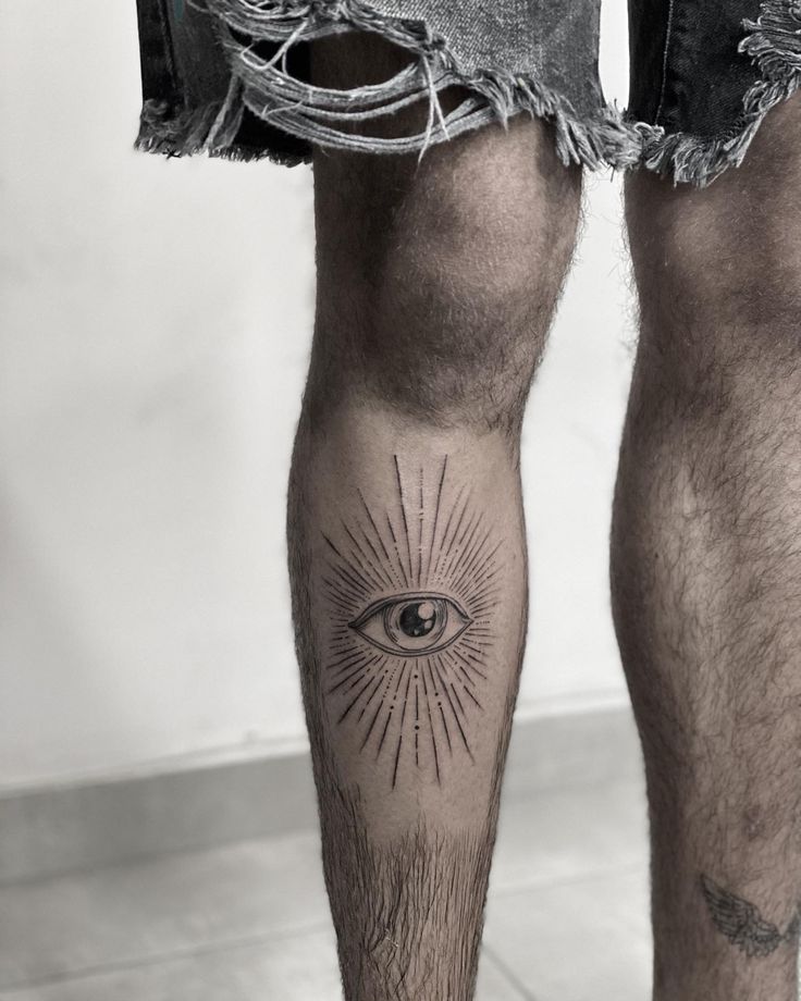 a man's leg with an all seeing eye tattoo on it and ripped shorts