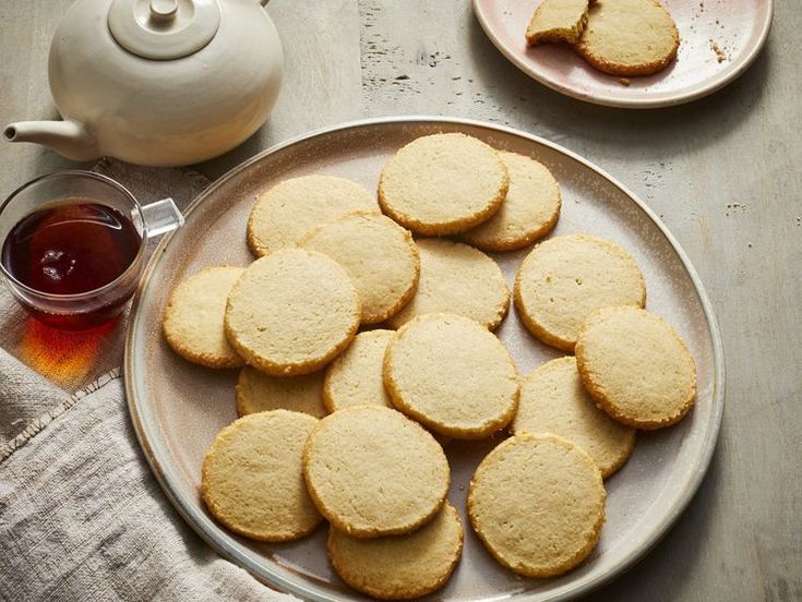 some cookies are on a plate next to a tea pot and a glass of tea