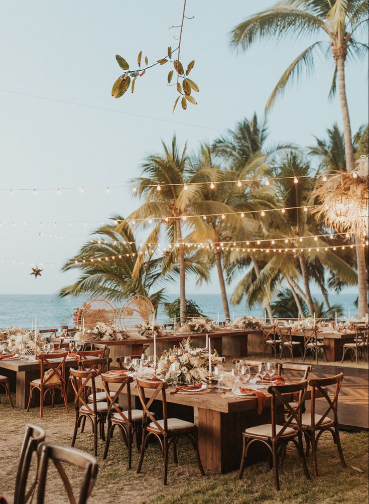 an outdoor dining area with palm trees and string lights