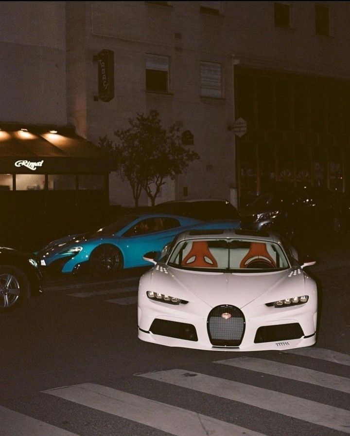 two cars parked in front of a building on the side of the road at night