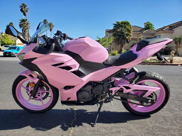 a pink and black motorcycle parked in a parking lot