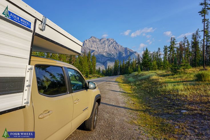 a truck parked on the side of a road with a camper in the back