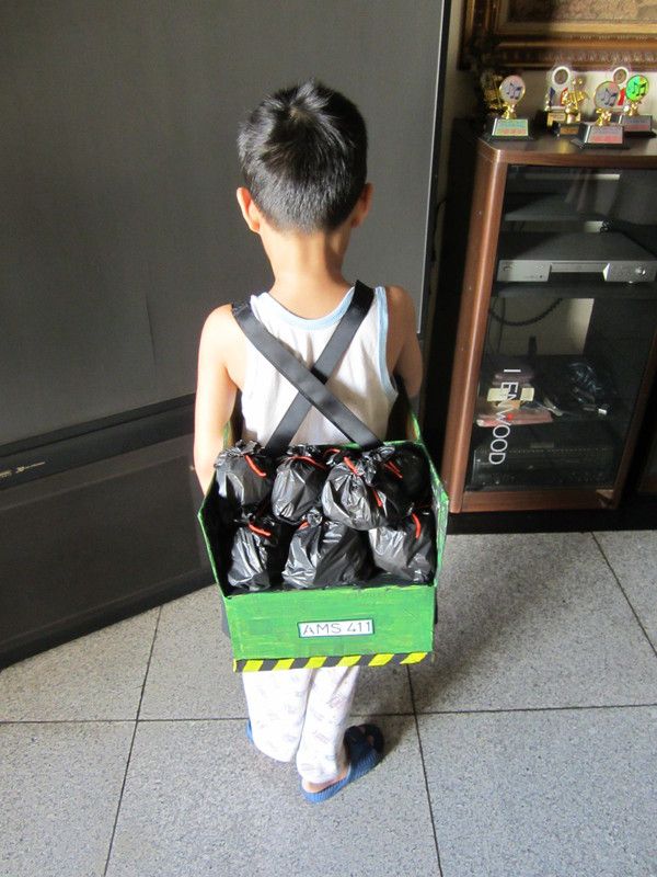 a young boy holding a green box full of garbage