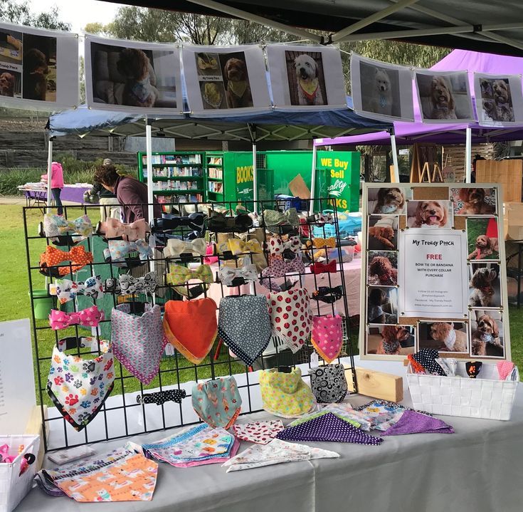 an outdoor market with many items for sale on the table and pictures hanging from racks