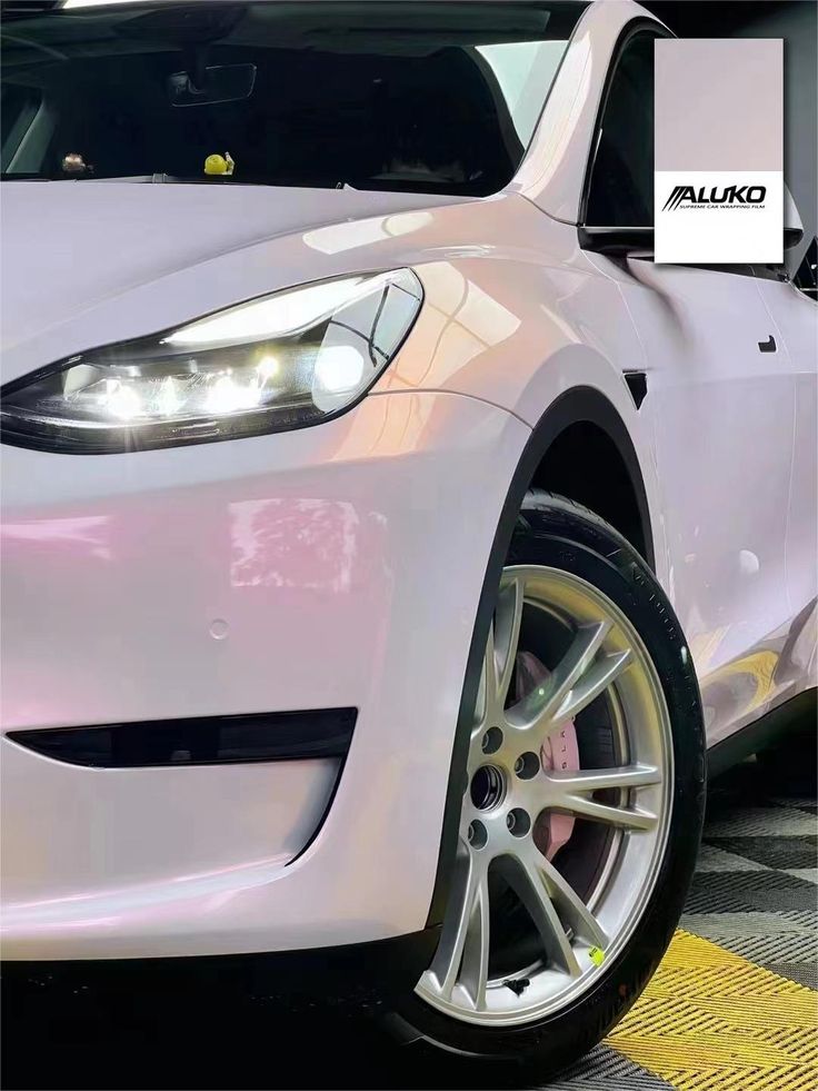 the front end of a white car parked in a parking lot