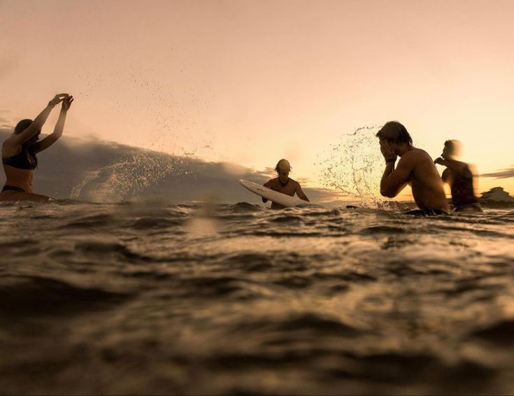 three people in the water with their surfboards