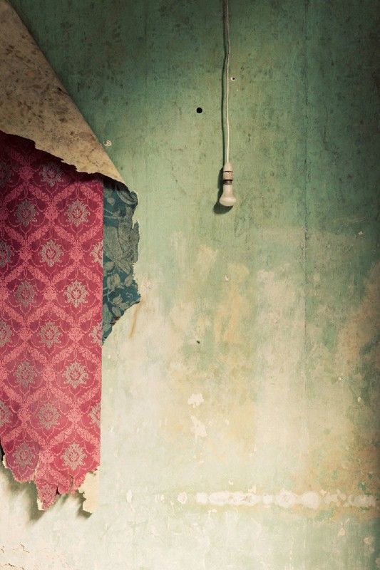 a red and blue tie hanging on a green wall next to a light fixture in an old room