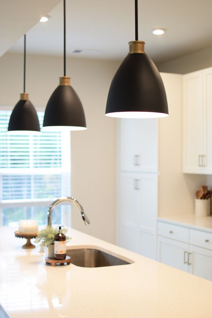 three lights are hanging over the kitchen counter