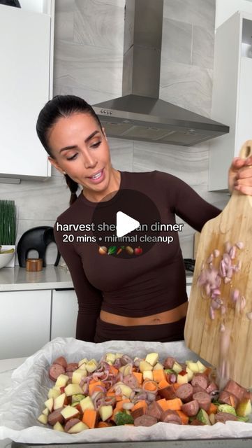 a woman holding a wooden cutting board over a pan filled with chopped vegetables and meat