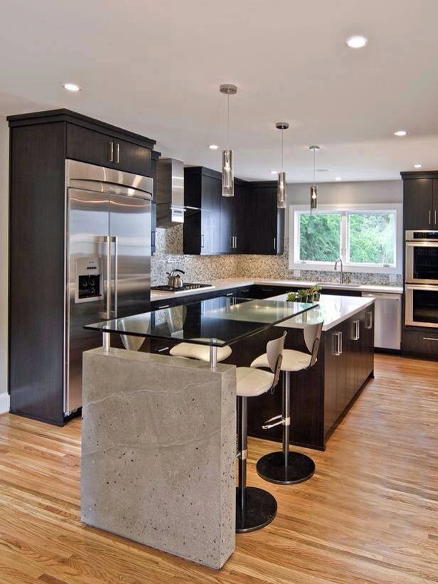 a modern kitchen with stainless steel appliances and black cabinets, wood floors, and hardwood flooring