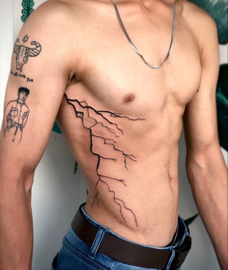 a man with a mountain tattoo on his chest is standing in front of a wall