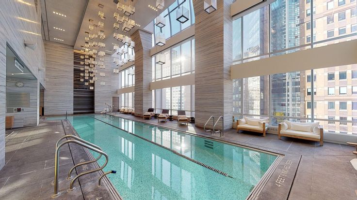 an indoor swimming pool in the middle of a large building with high ceilings and floor to ceiling windows