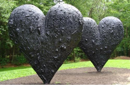 three metal hearts sitting in the middle of a park