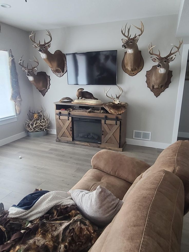 a living room with deer heads mounted to the wall and a flat screen tv above it