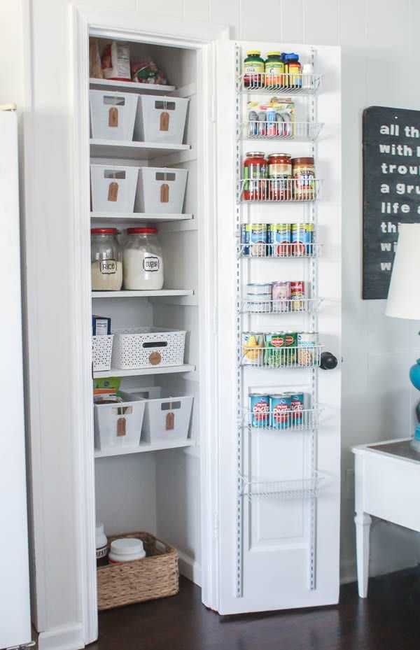 an organized pantry with white shelves and bins