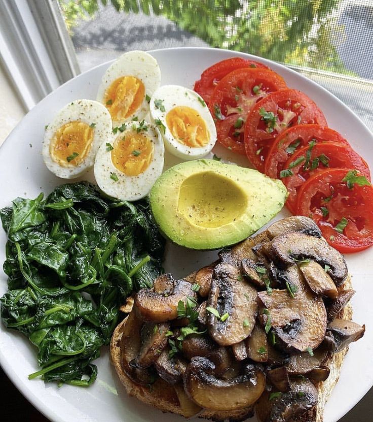 a white plate topped with eggs, mushrooms and veggies