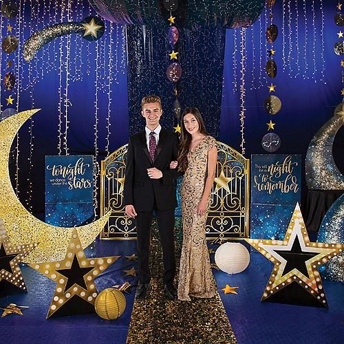 a man and woman standing in front of a stage set with stars, moon and ball decorations