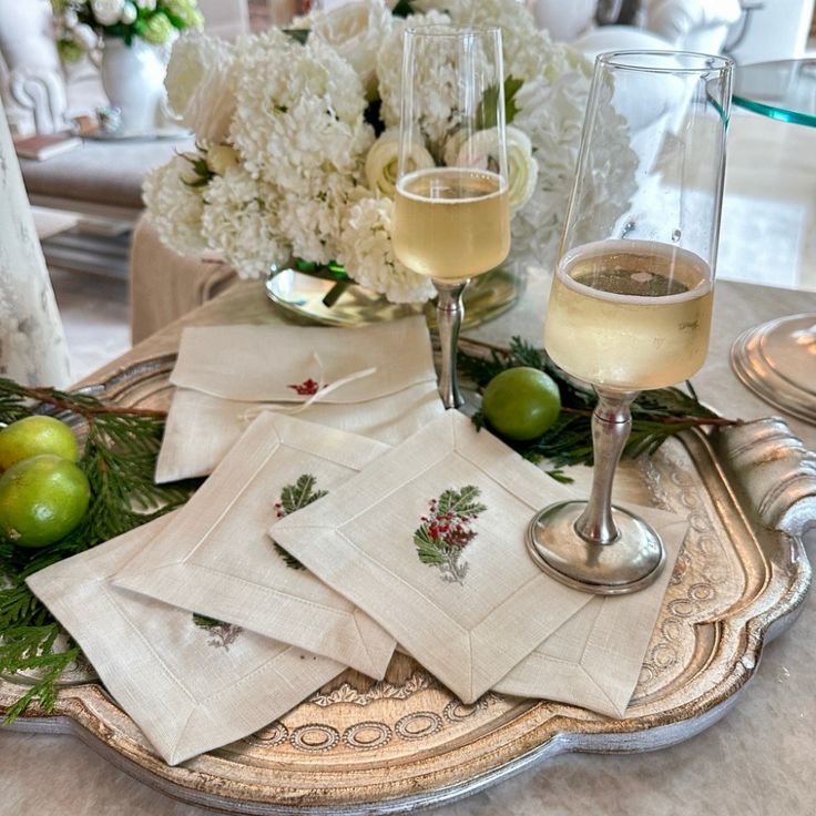 two glasses of wine on a tray with napkins and flowers in the centerpiece