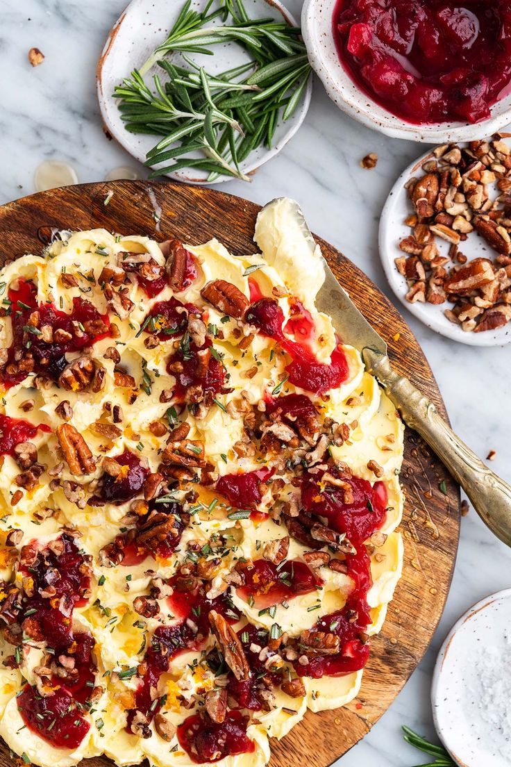 a pizza sitting on top of a wooden cutting board next to bowls of toppings