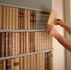 a man is placing books on a book shelf