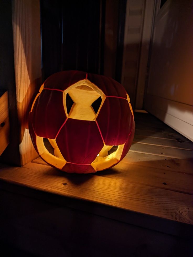 a lit up pumpkin sitting on top of a wooden shelf