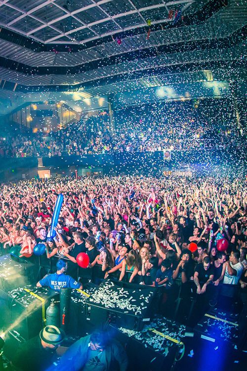 a large group of people at a concert with confetti falling from the ceiling