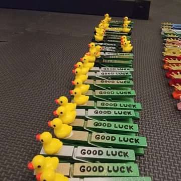 rows of rubber ducks lined up on the floor in front of an advertisement for good luck