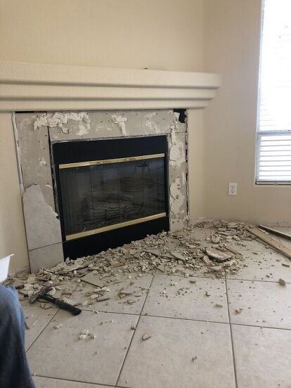 a living room with a fireplace that has been torn apart and the floor is covered in debris