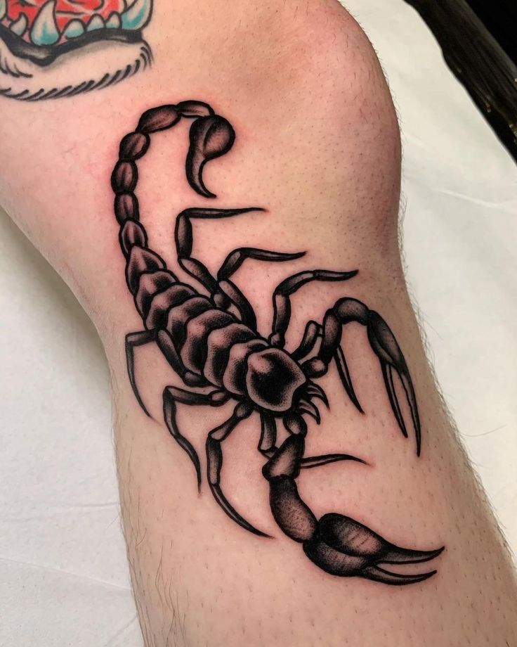 a black scorpion tattoo on the leg