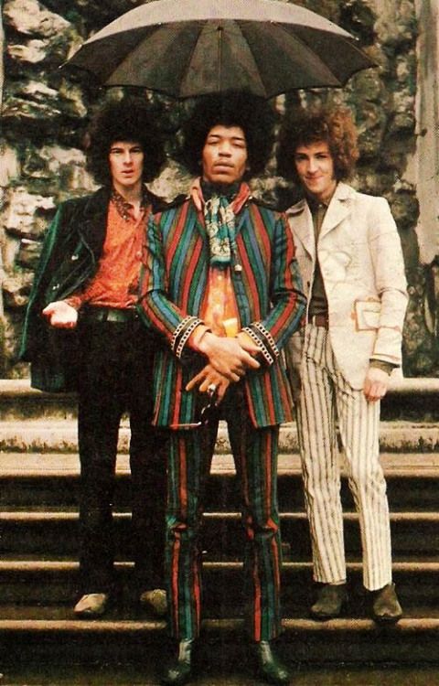 three men standing under an umbrella in front of stairs