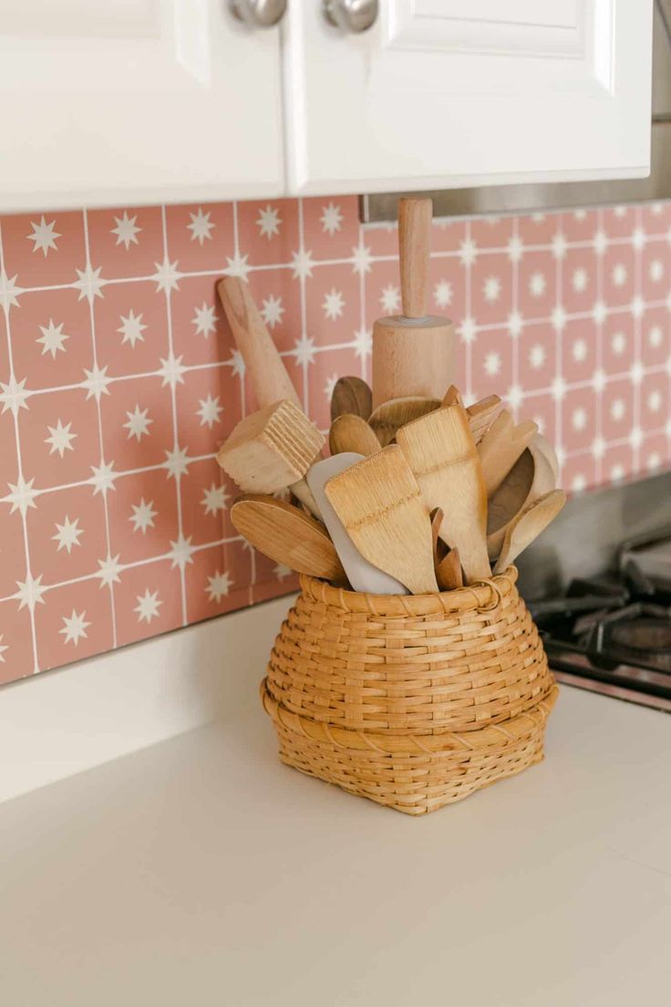 a basket filled with wooden utensils sitting on top of a counter next to a stove