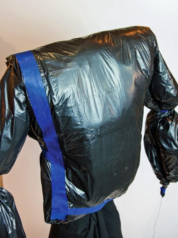 the back of a black plastic jacket with blue straps