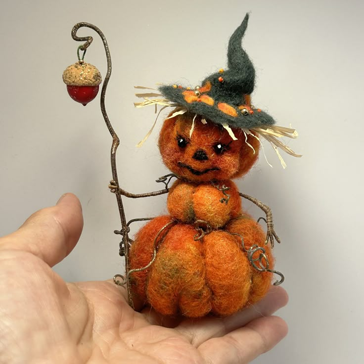 a hand holding an orange stuffed animal with a witch hat