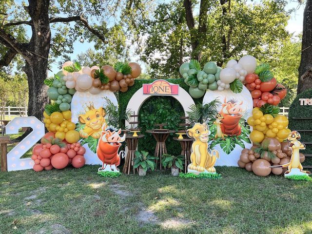 an outdoor birthday party with balloons, fruit and animals on the front lawn at a zoo