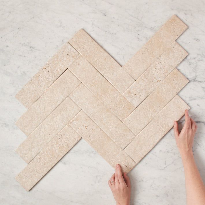 a person is laying tile on the floor with their hands in front of them and pointing at it