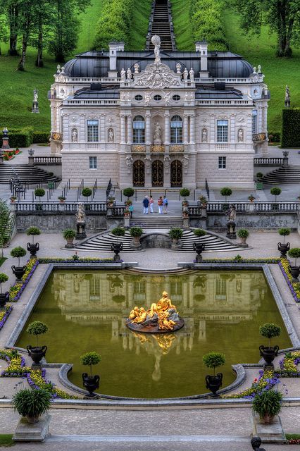 an aerial view of a large building in the middle of a park with fountains and trees