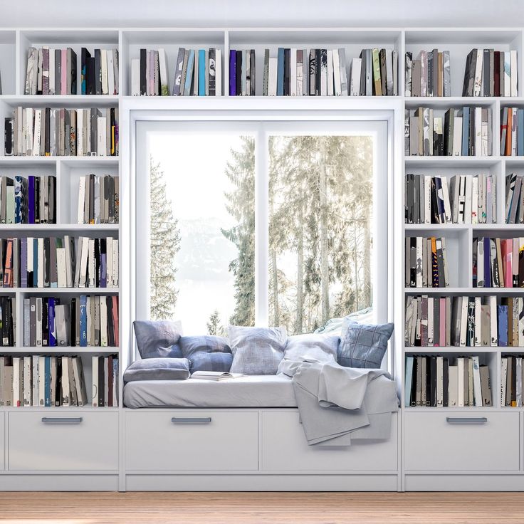 a window seat in front of a bookcase filled with lots of books and pillows