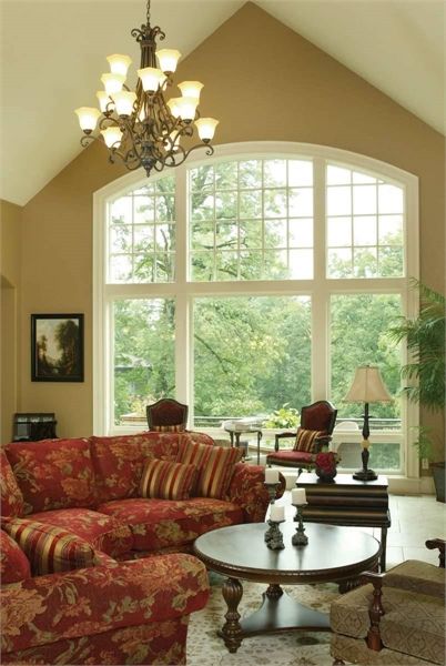 a living room filled with furniture and a large window covered in lots of windows above it