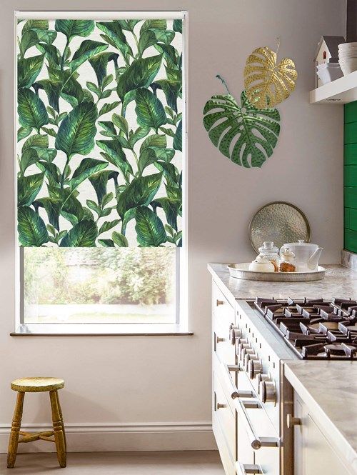 the kitchen is decorated in green and white with tropical prints on the wall behind the stove