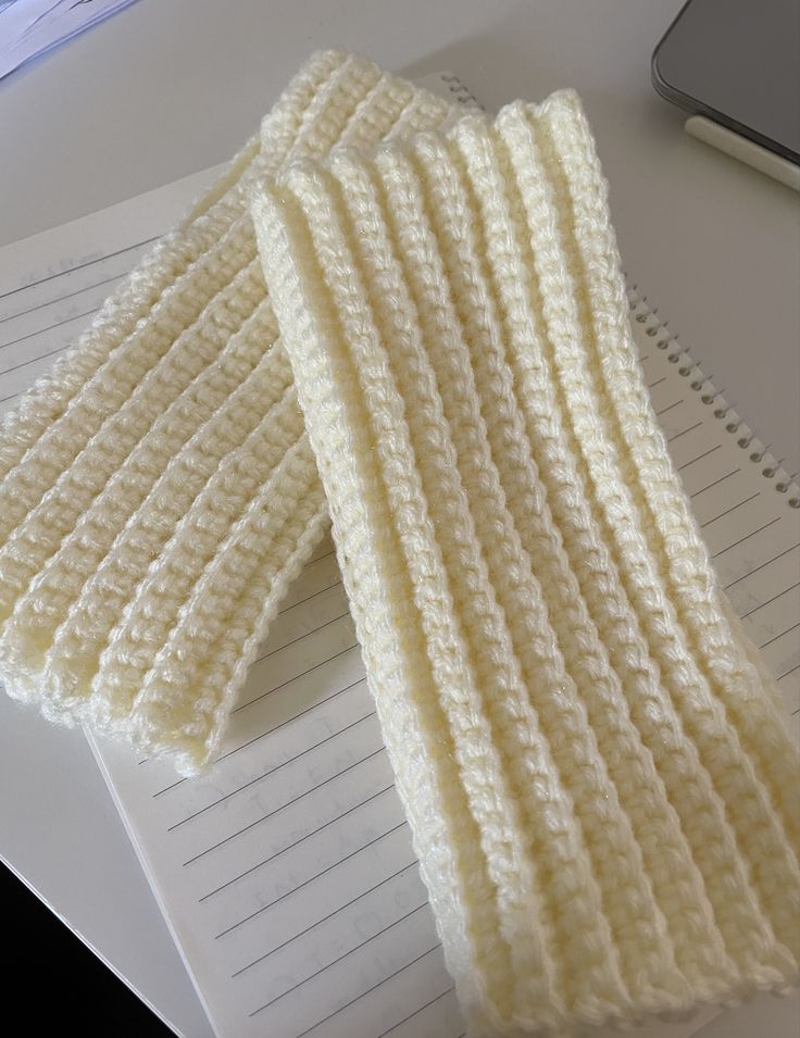 two crocheted white gloves sitting on top of a desk next to a laptop computer