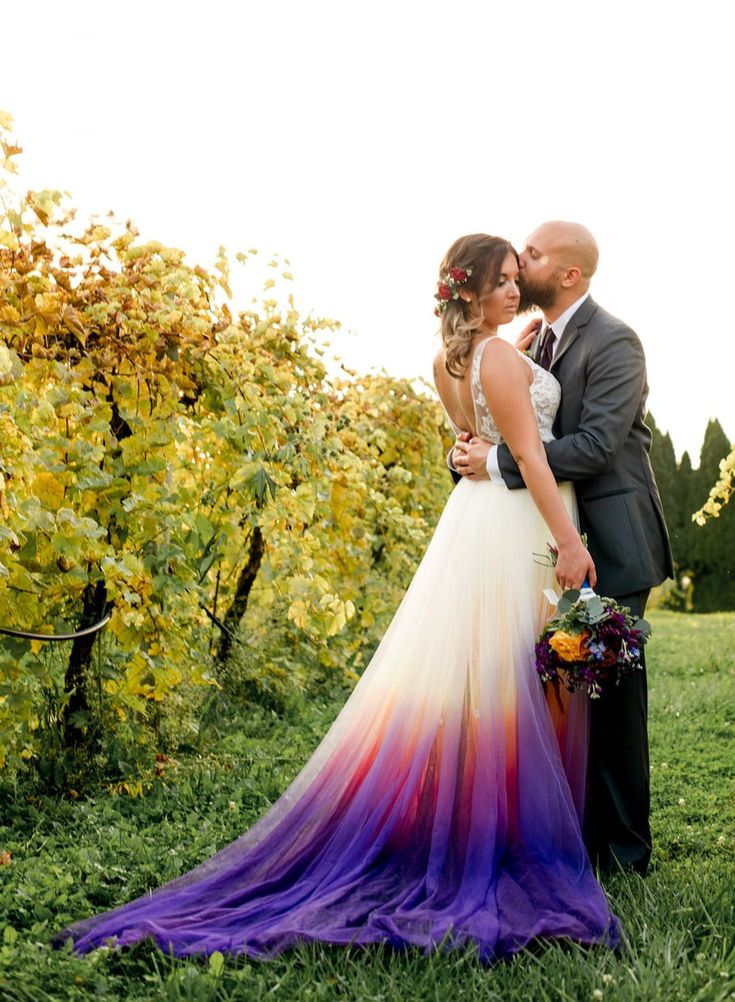 a bride and groom standing in the middle of a field next to some grapes bushes