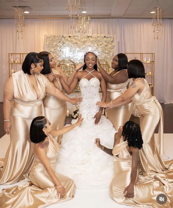 a group of women standing around each other in front of a wedding dress on display