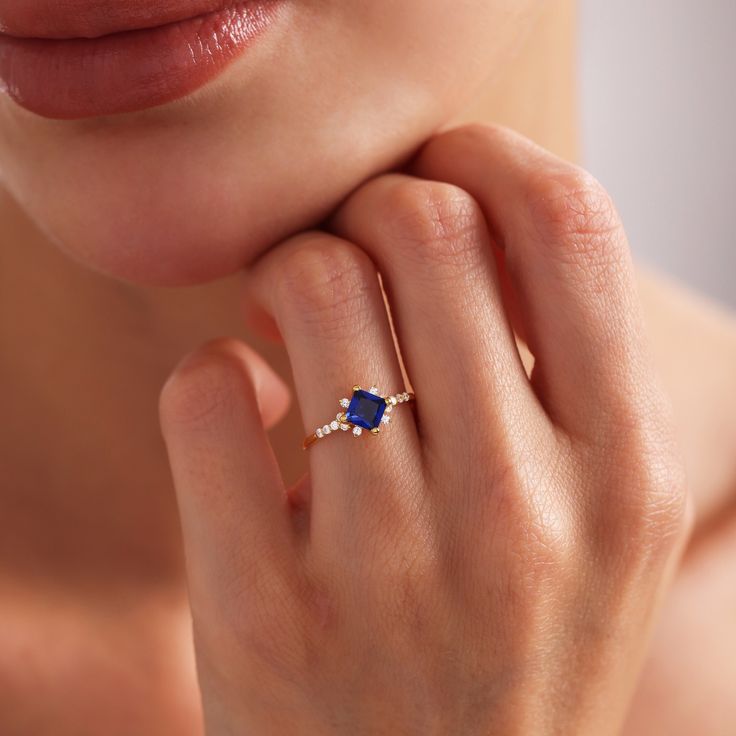 a woman's hand with a diamond and blue sapphire ring on her left finger